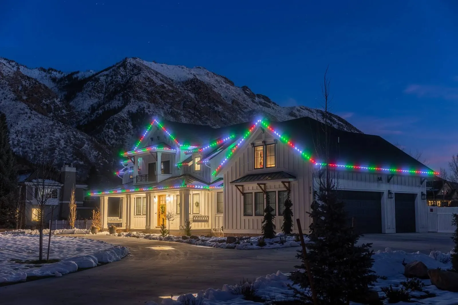 Snowy home decorated with multicolor Christmas lights along the roofline