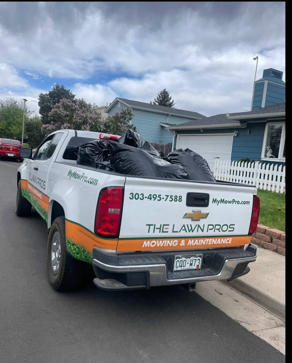 The Lawn Pros work truck loaded with bagged yard debris outside a home