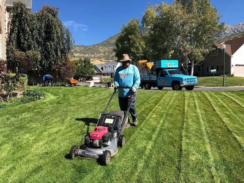 Lawn care worker push mowing a striped residential front lawn